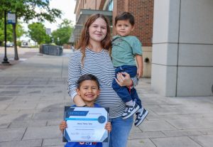 mother with her two children holding diploma outside on campus