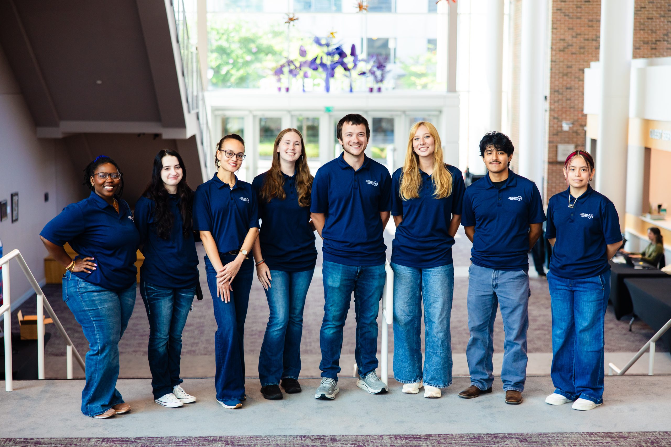 student ambassadors smiling in line on college campus
