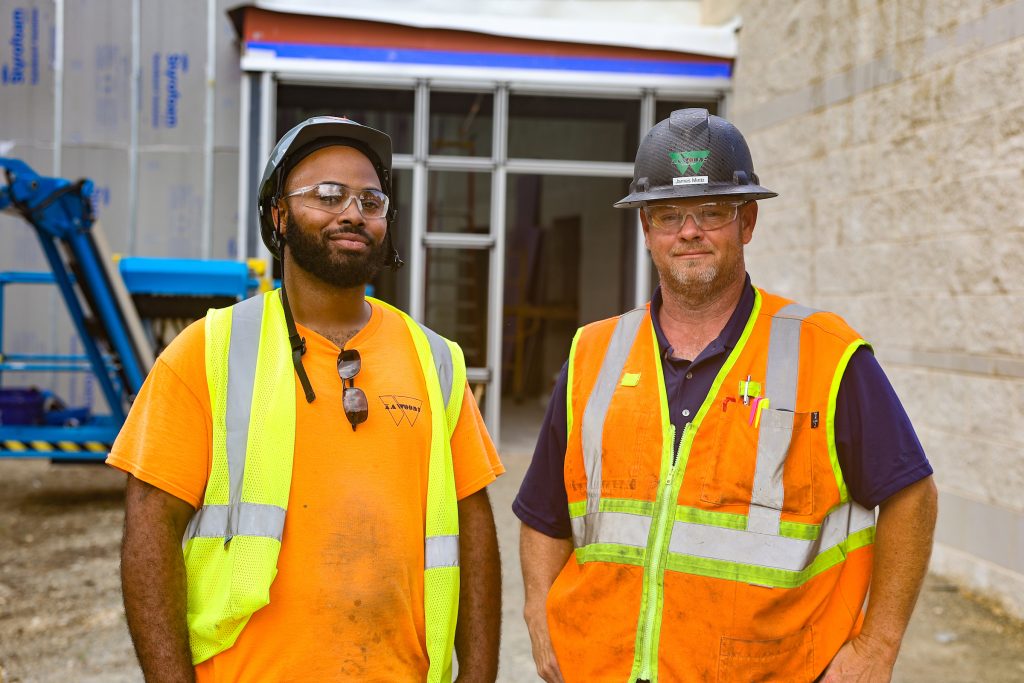 two construction workers in front of job site