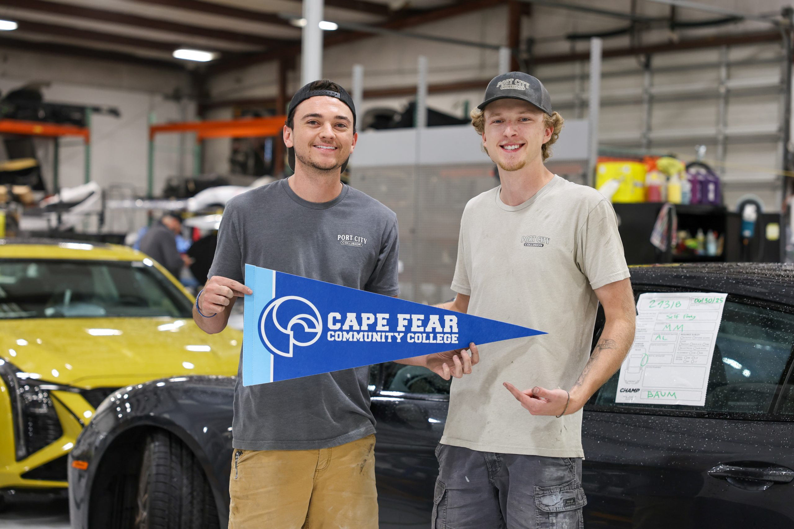 Two men smile inside an auto body shop