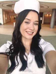 female nursing in graduation scrubs taking a selfie