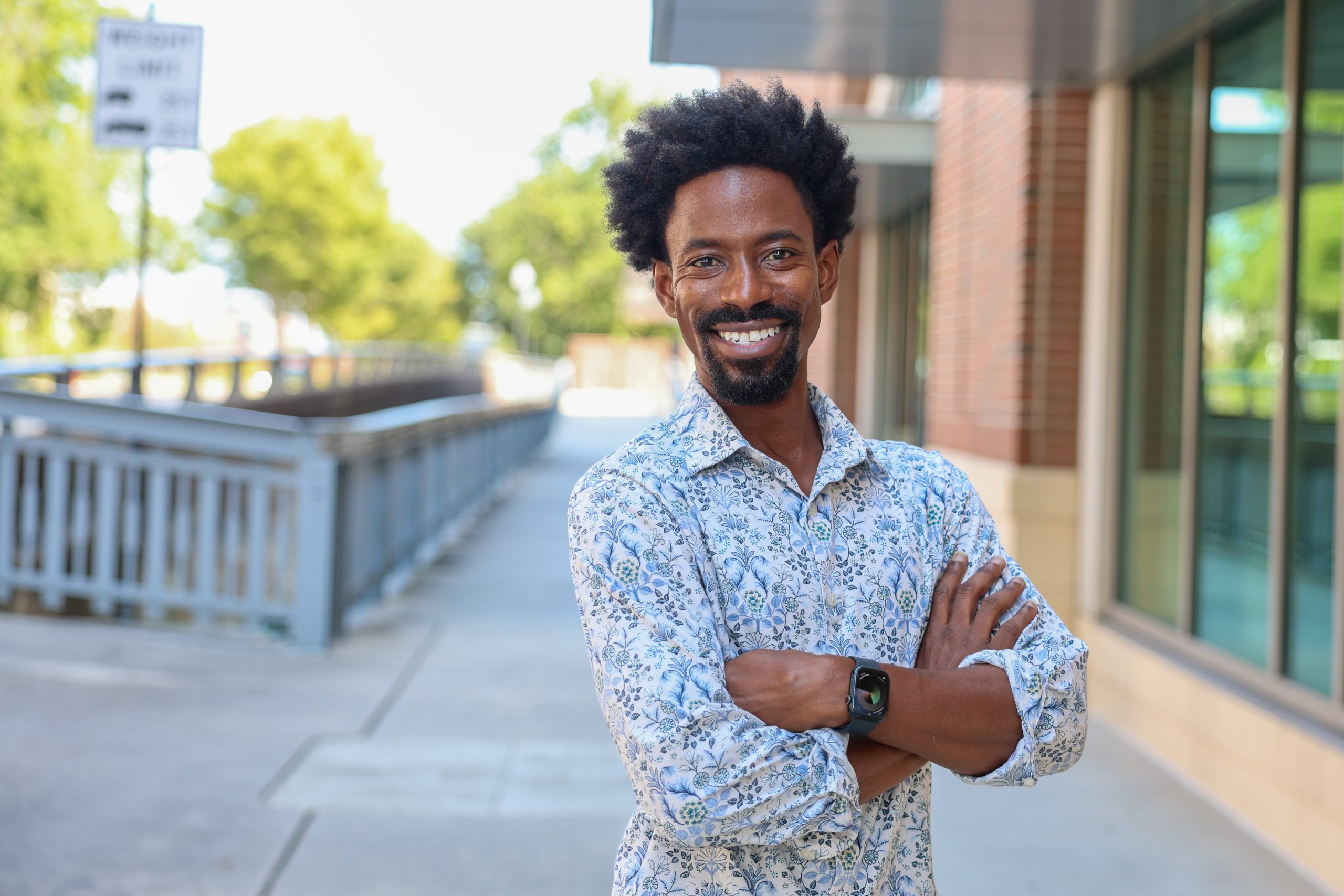 Student smiling and standing with his arms crossed.