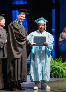 student holding diploma next to president