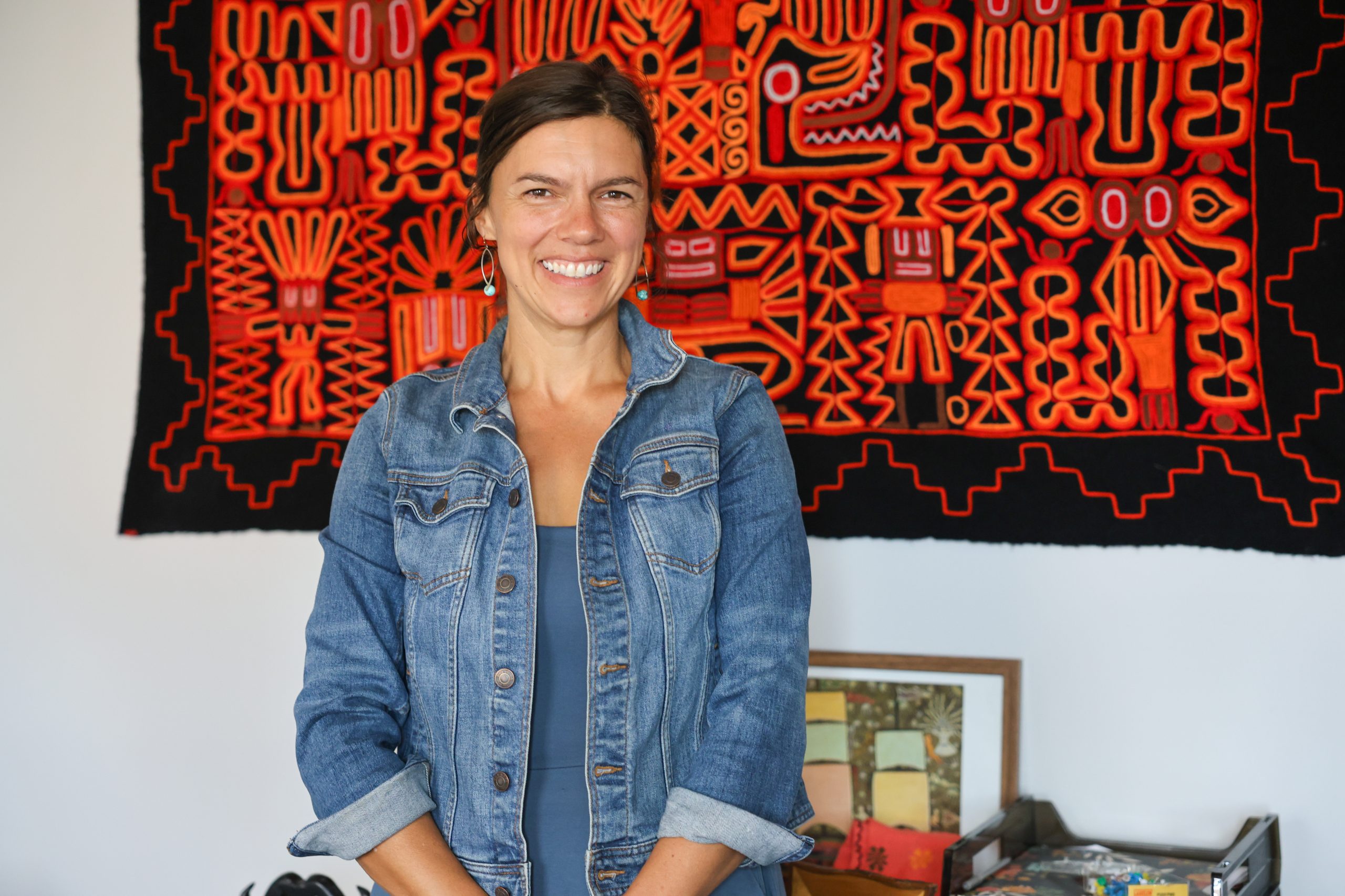 Female smiling in front of red tapestry