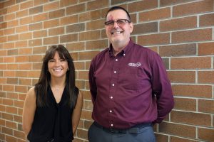 alumni with instructor in front of brick wall