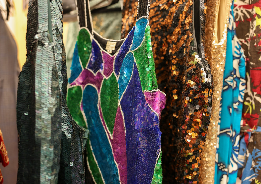 Colorful sequin dresses hanging from a rack.