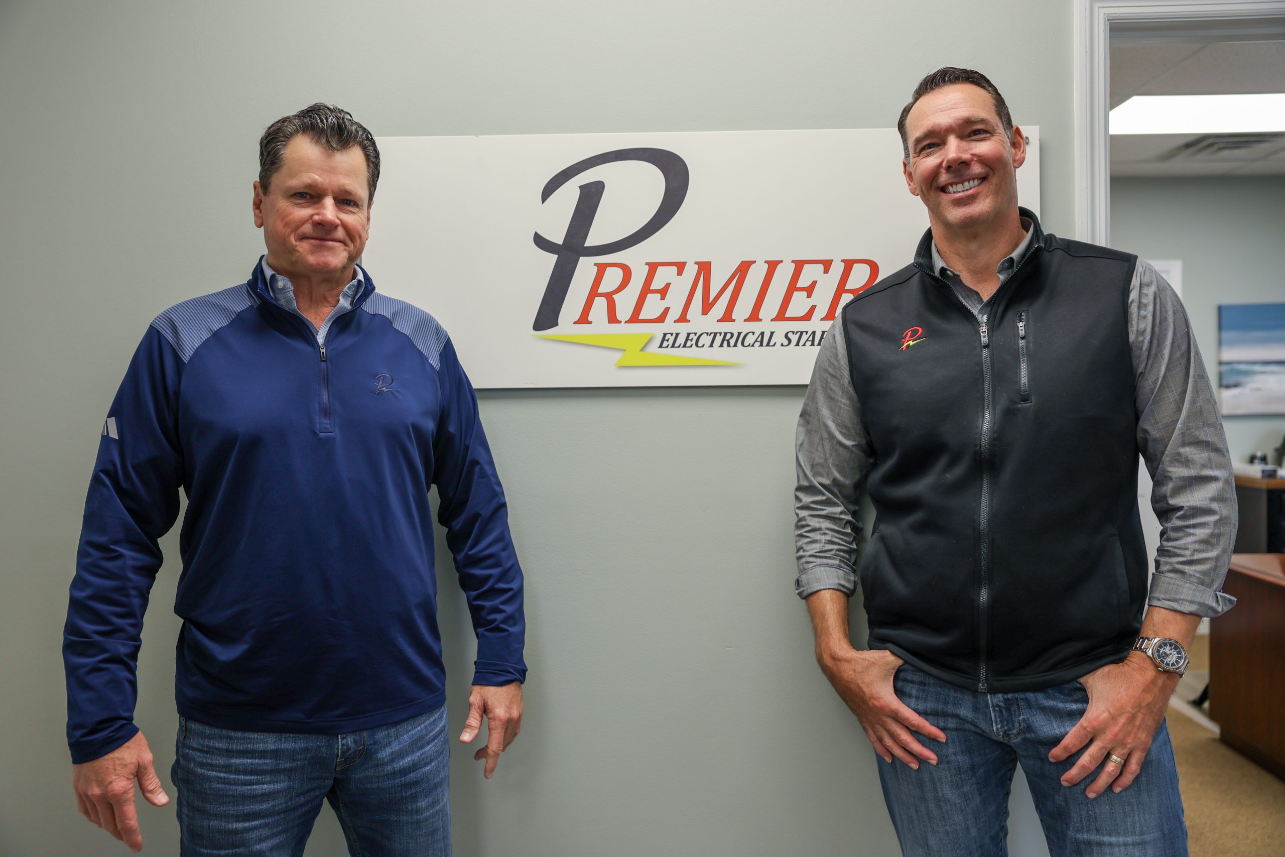two men standing in front of premier sign
