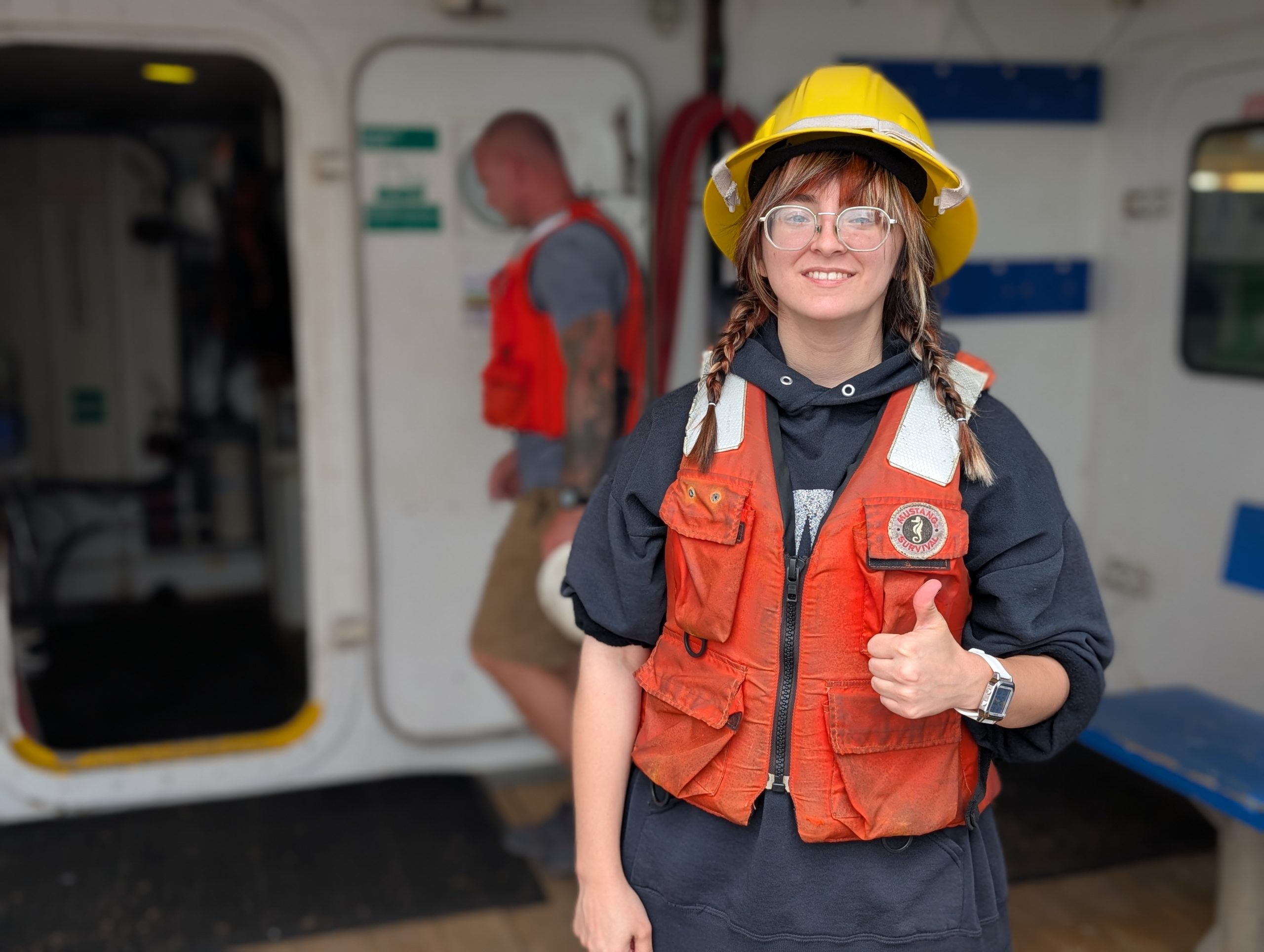 female aboard research vessel giving a thumbs up