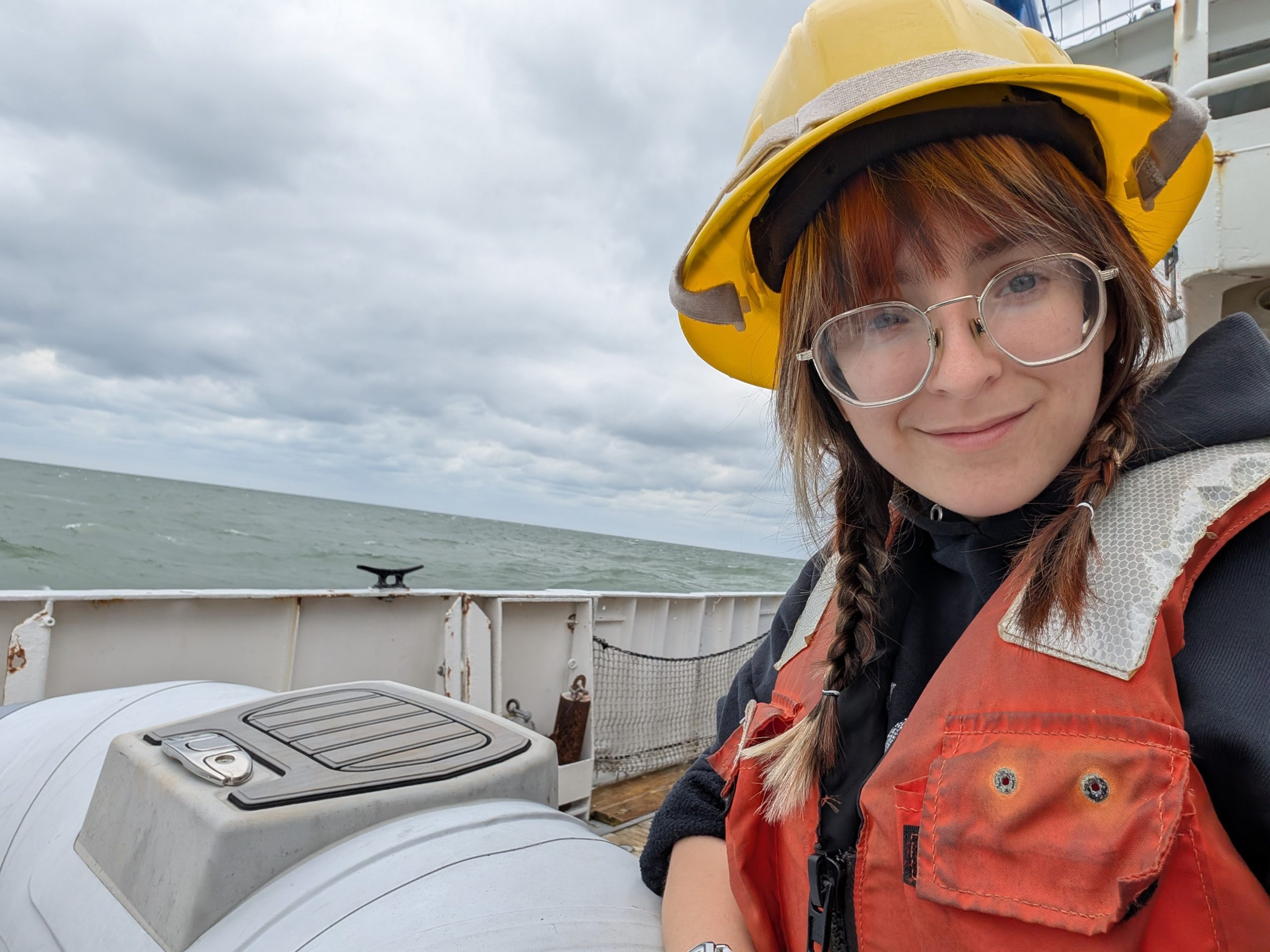 female marine tech student aboard ship taking a selfie with ocean in background