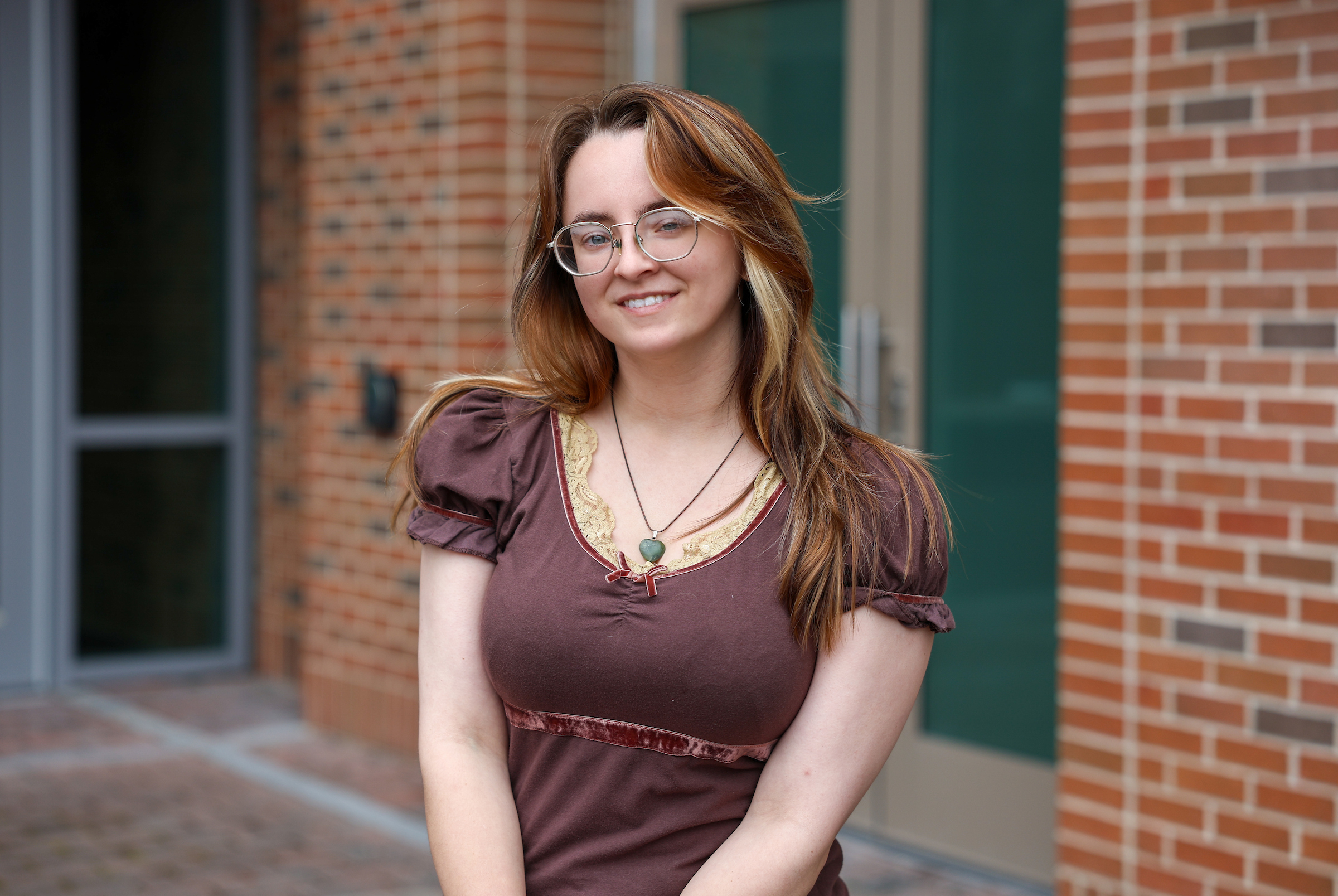 female standing outside of college campus building smiling