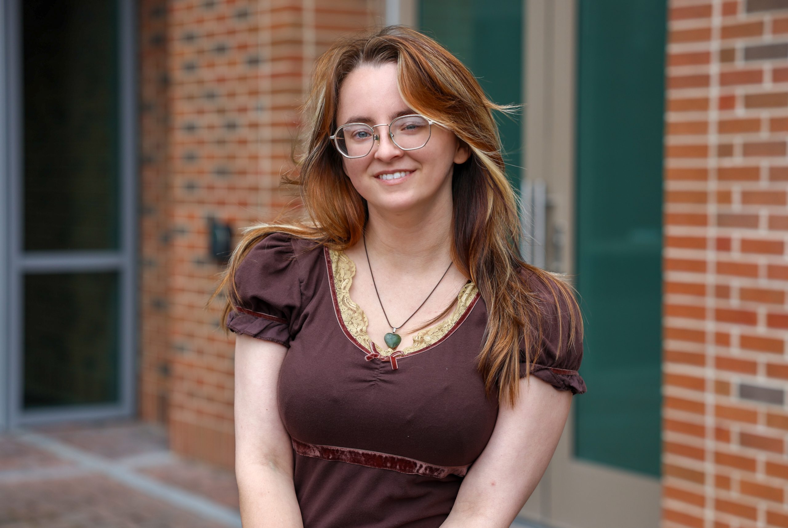 female standing outside of college campus building smiling
