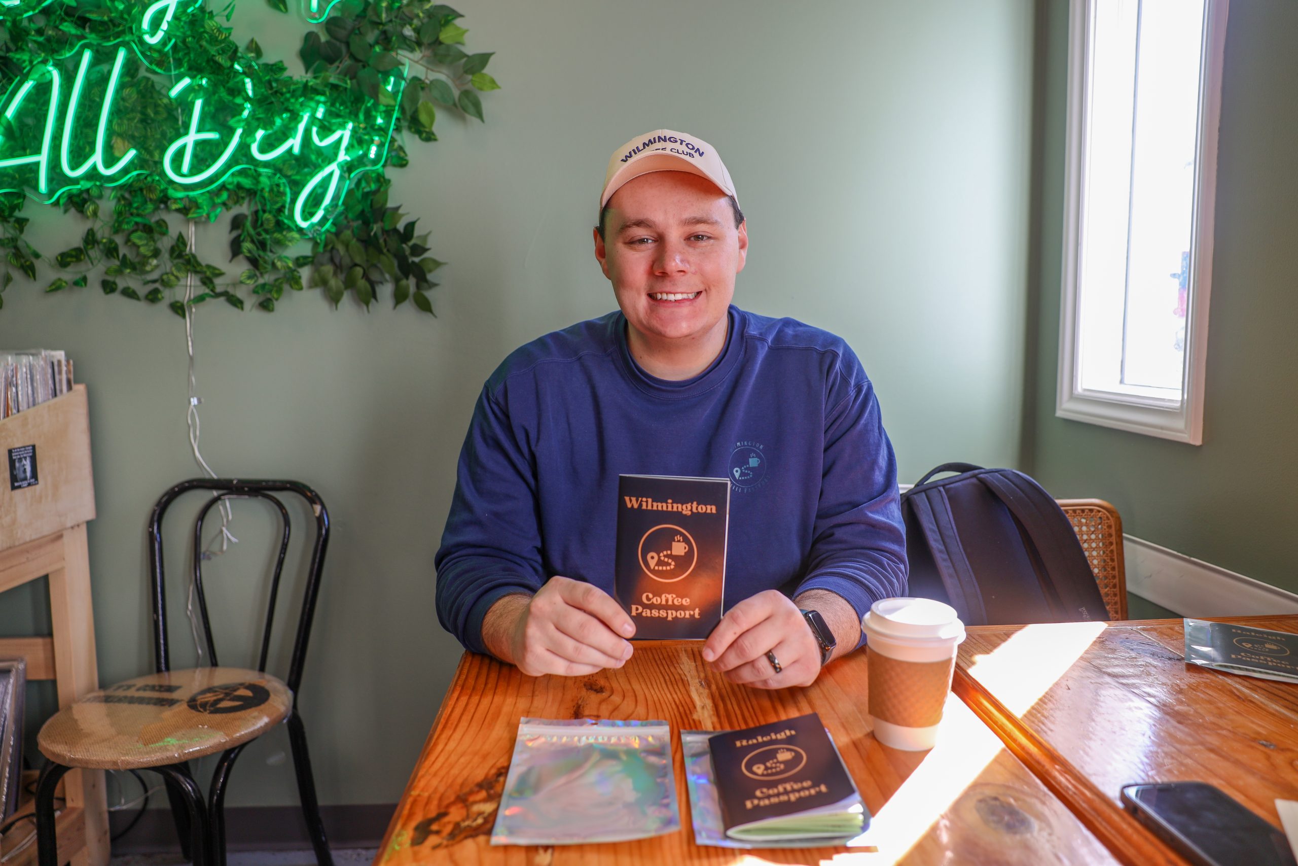 man sitting at a table in a coffee shop holding a coffee passport
