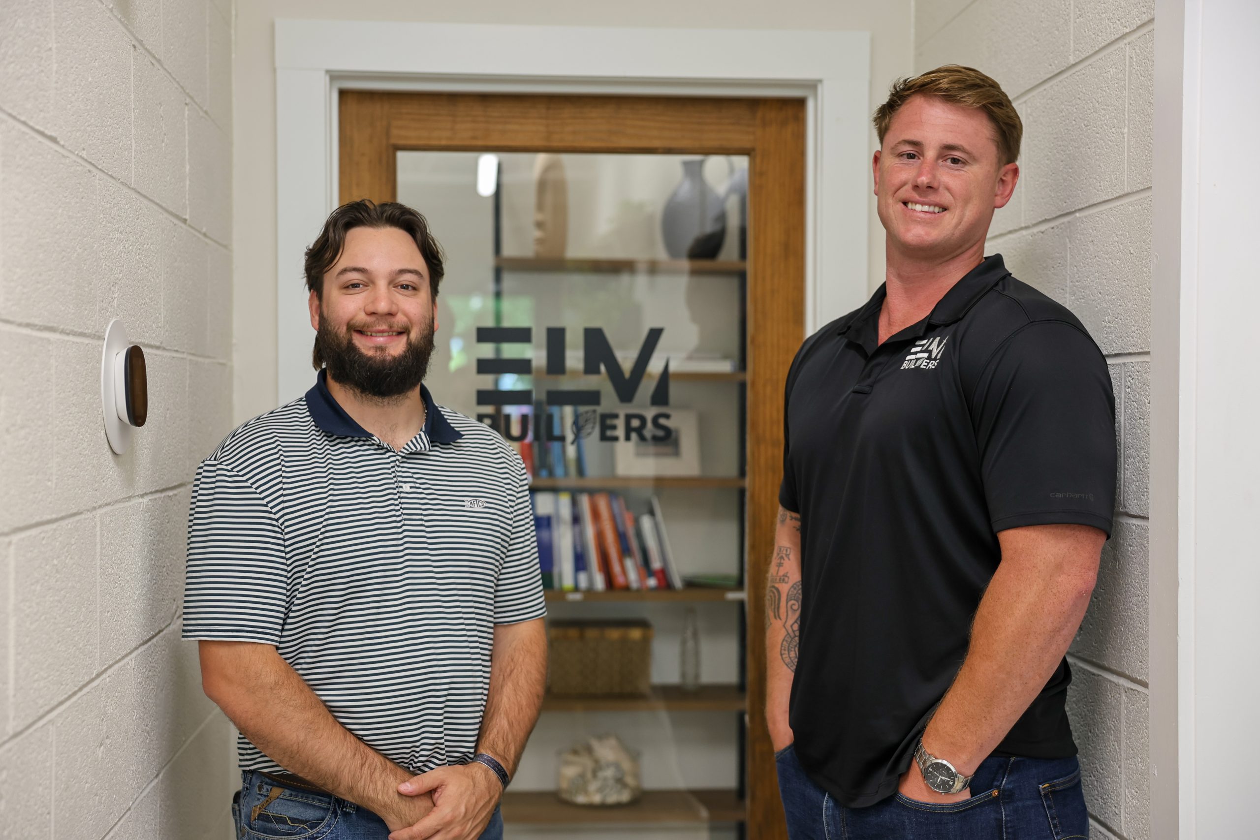 two men standing in office with an elm building logo on the door behind them