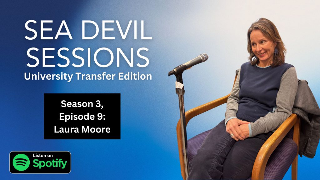 Sea Devil Sessions podcast promotional graphic for the “University Transfer Edition.” Large white text on a blue gradient background reads “SEA DEVIL SESSIONS” and “University Transfer Edition.” A black box states “Season 3, Episode 9: Laura Moore.” On the right, a woman sits in a cushioned chair, smiling and looking toward a standing microphone positioned in front of her. She wears a long-sleeve top and dark pants, with a jacket draped over the chair. A “Listen on Spotify” badge appears in the lower left corner.