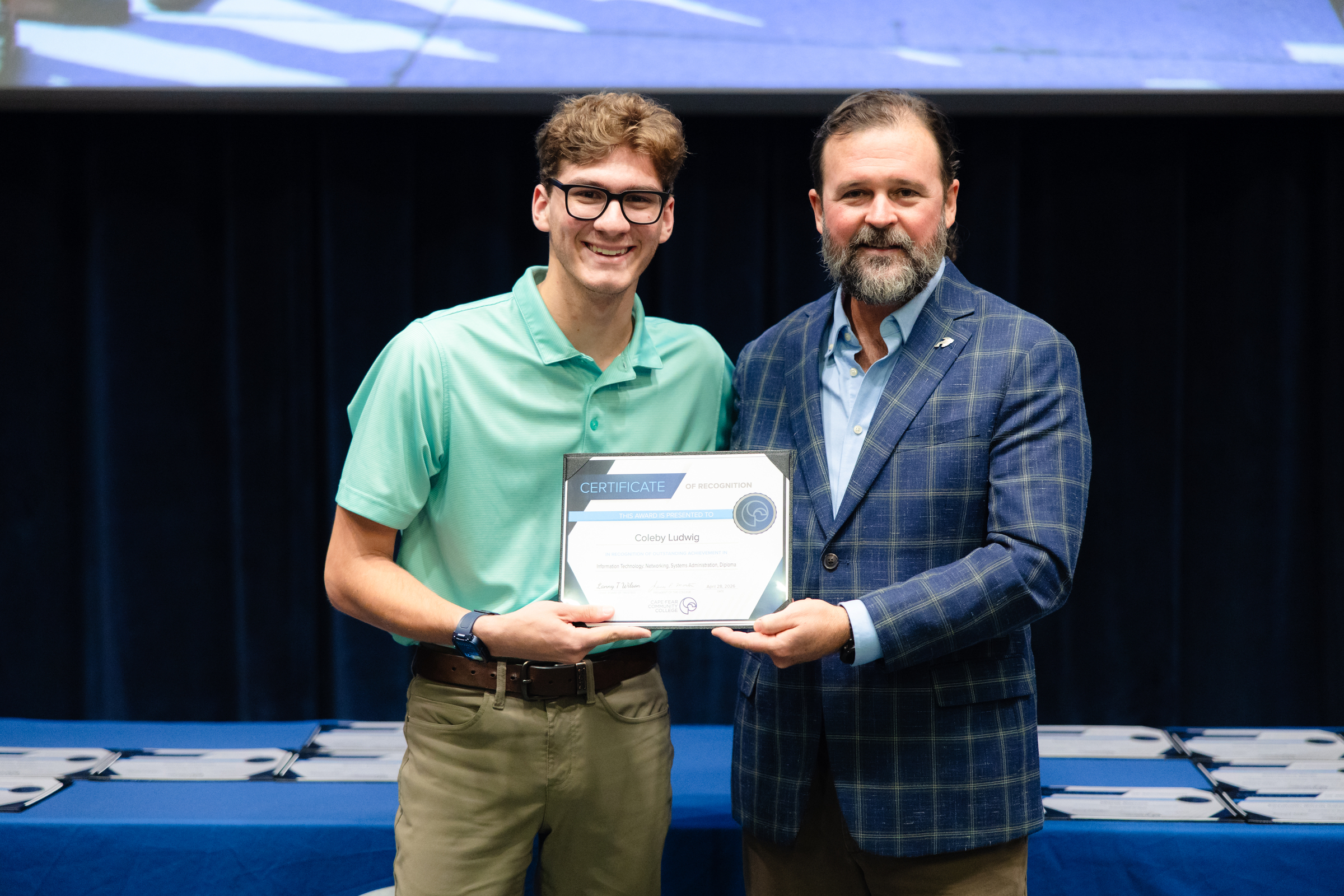 instructor and admin holding certificate at student recognition ceremony
