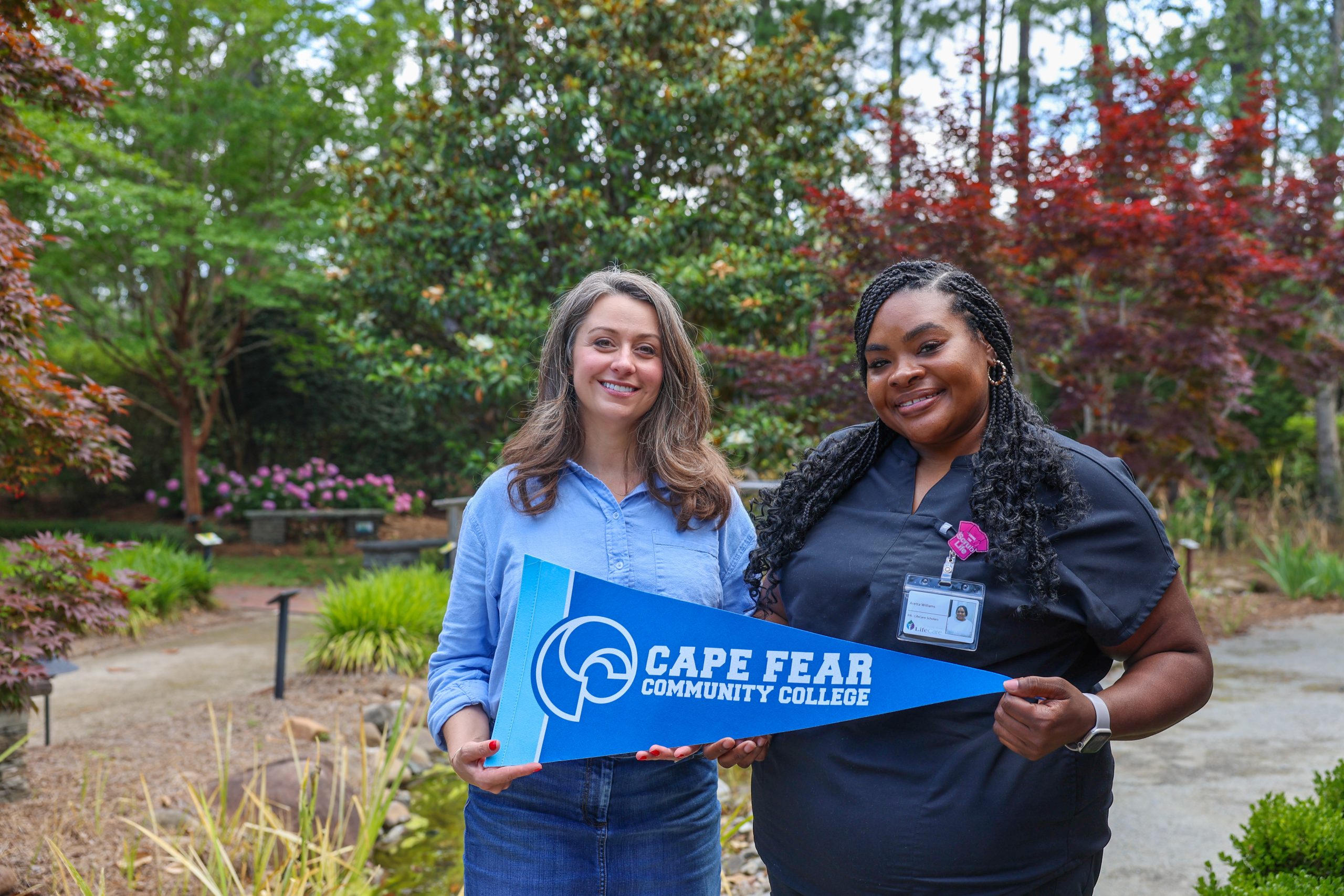 nursing graduates stand outside holding cfcc flags