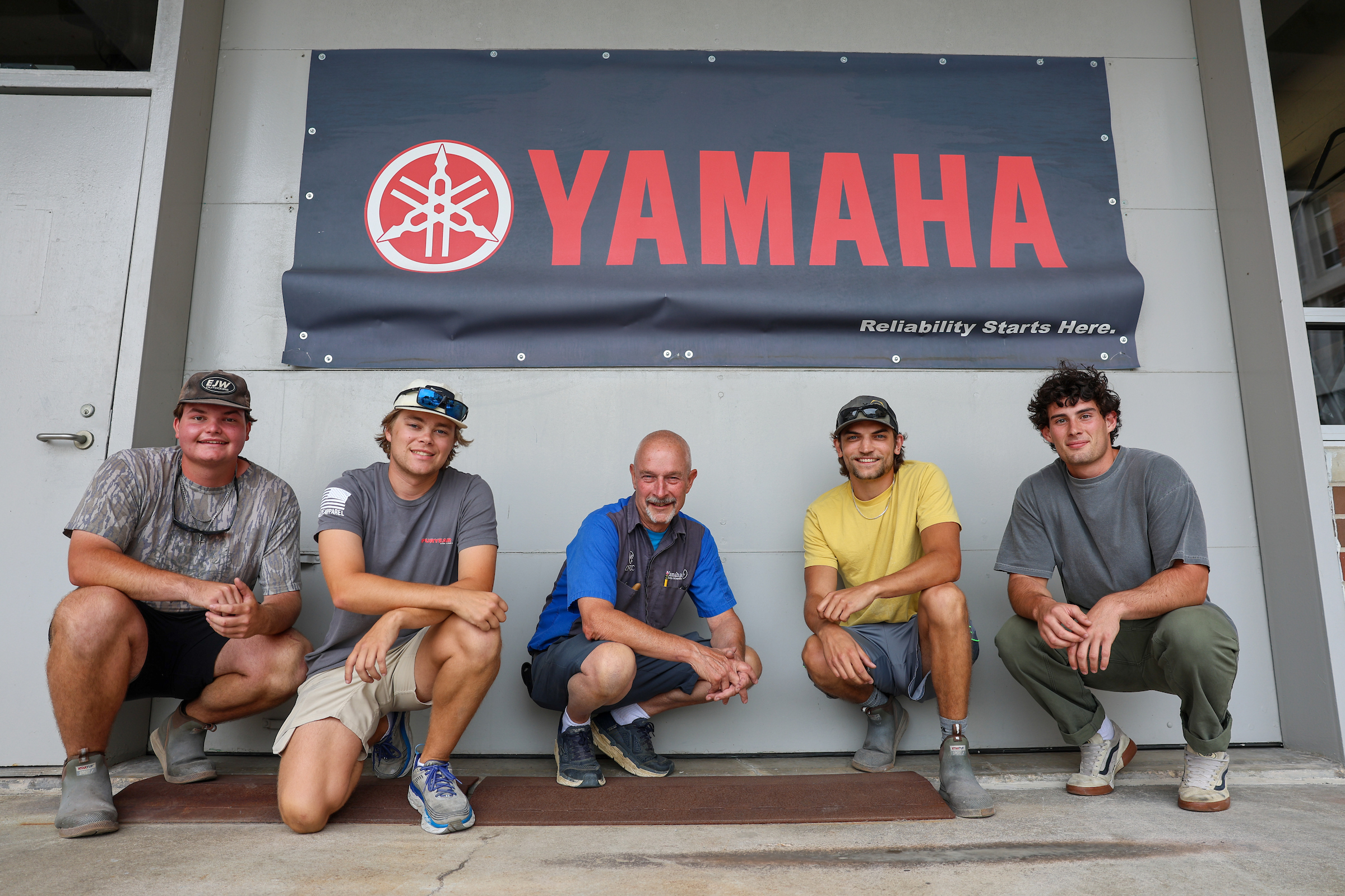 group of students and instructor standing in front of Yamaha sign