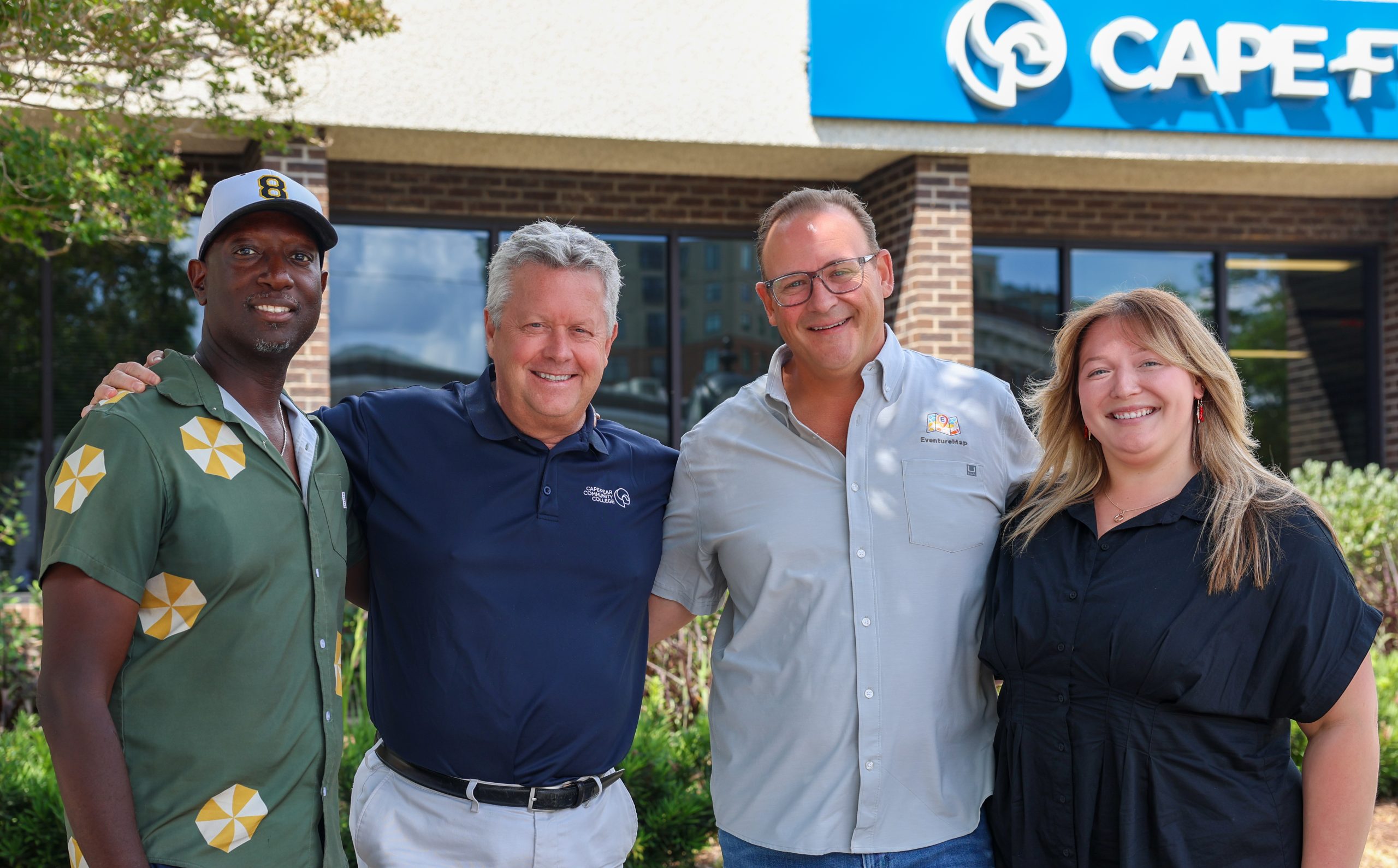 group of four people stand outside college building