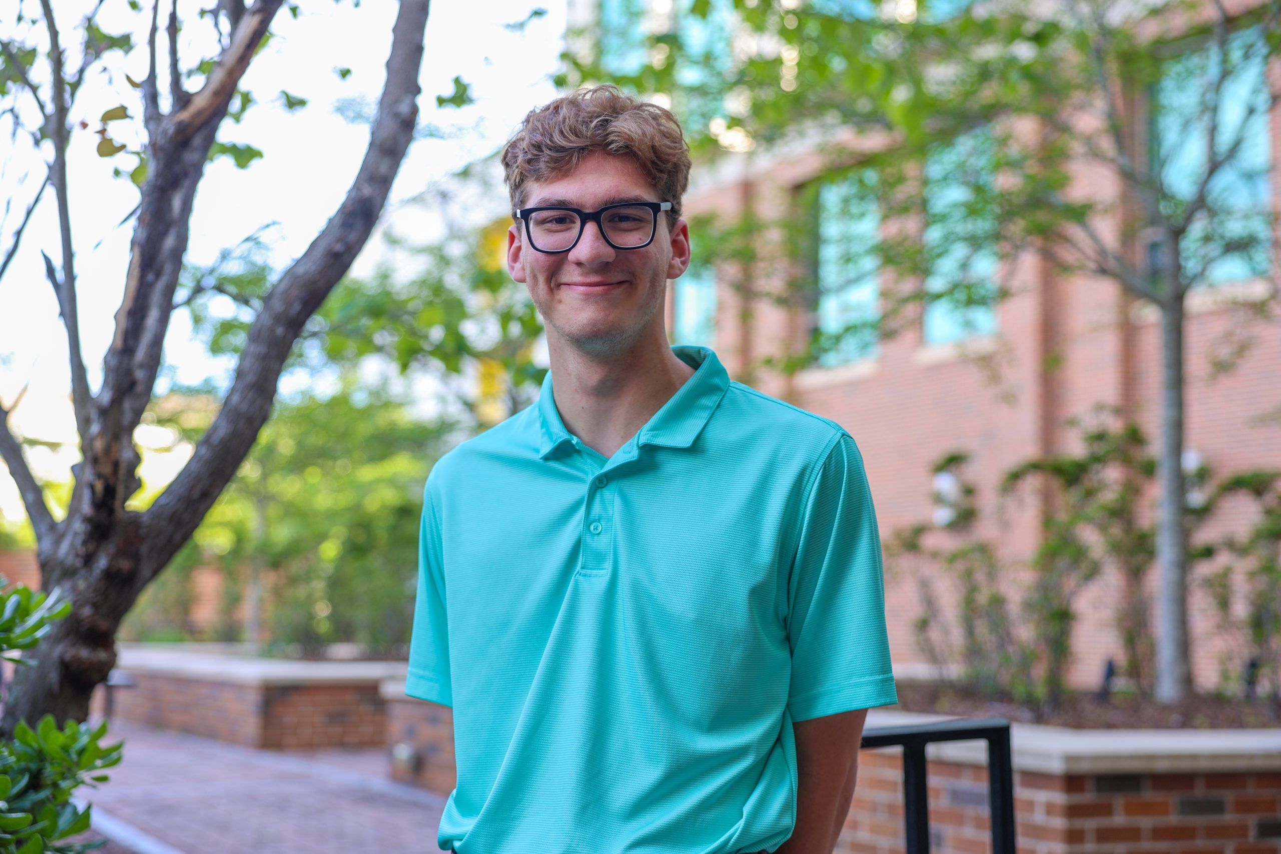 student standing outside of campus smiling