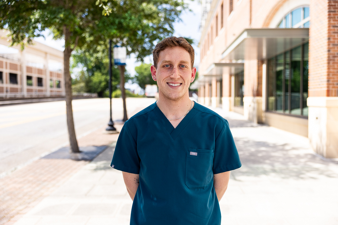 alumni wearing scrubs outside of campus