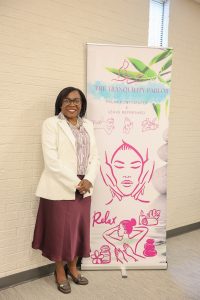 Woman in a white blazer and burgundy skirt smiling beside a Tranquility Parlor wellness and massage services banner.