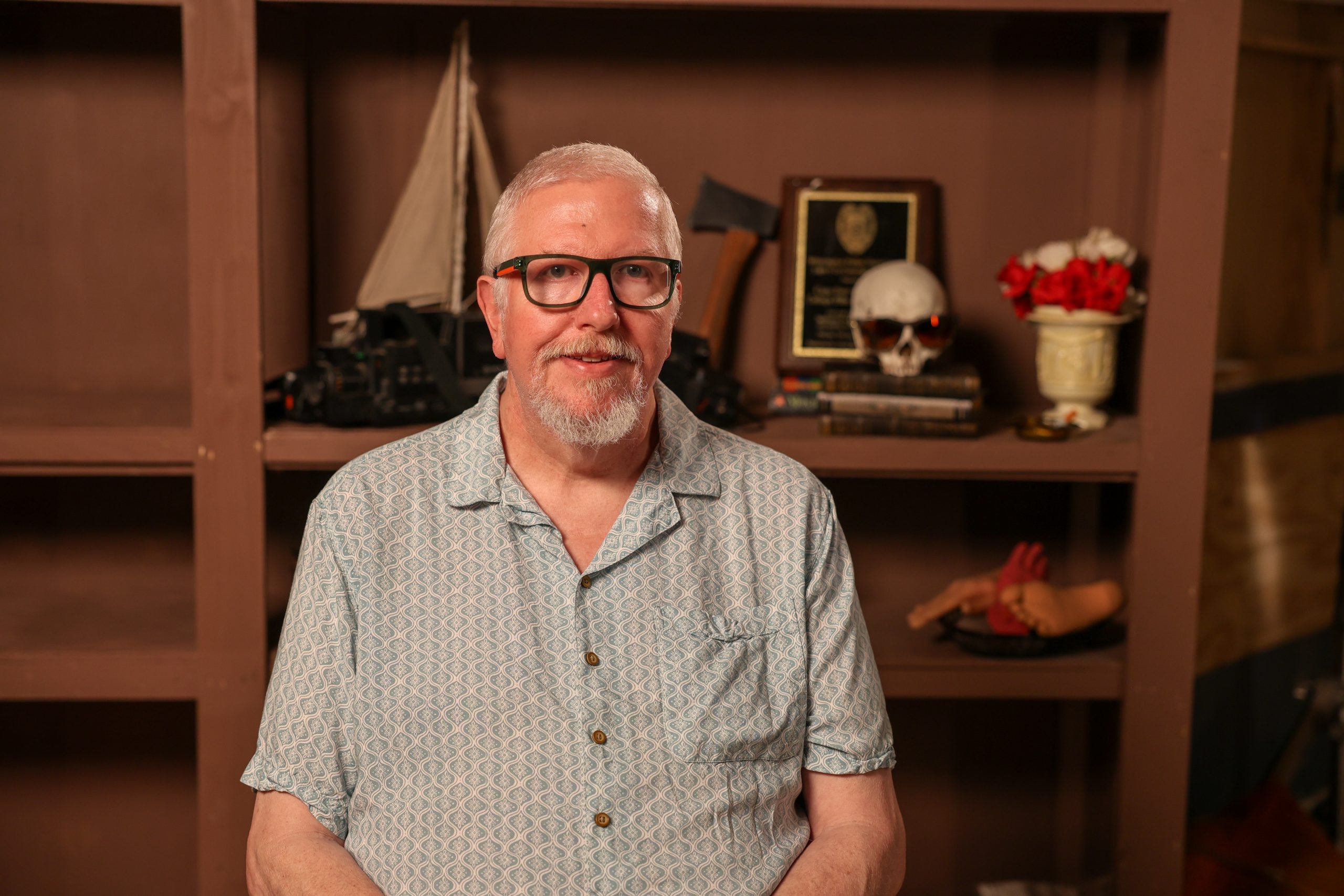 man seated behind bookshelves