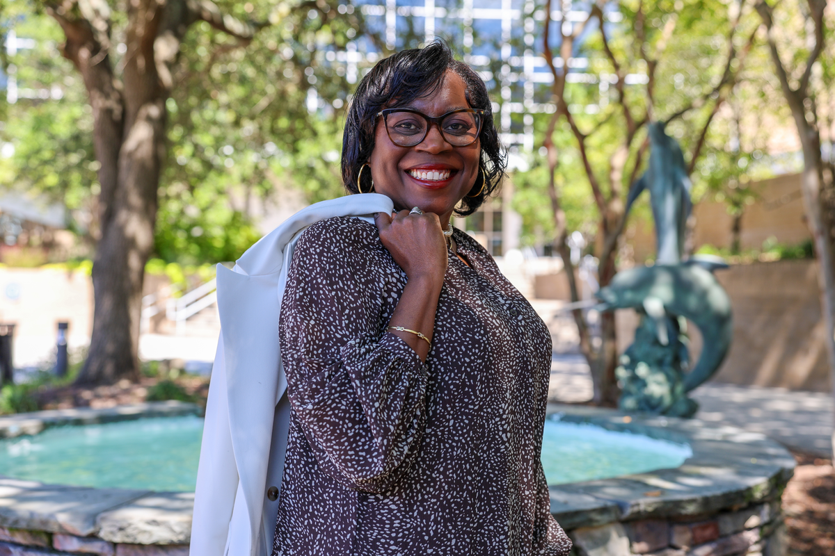 woman holding jacket over her shoulders posed behind fountain