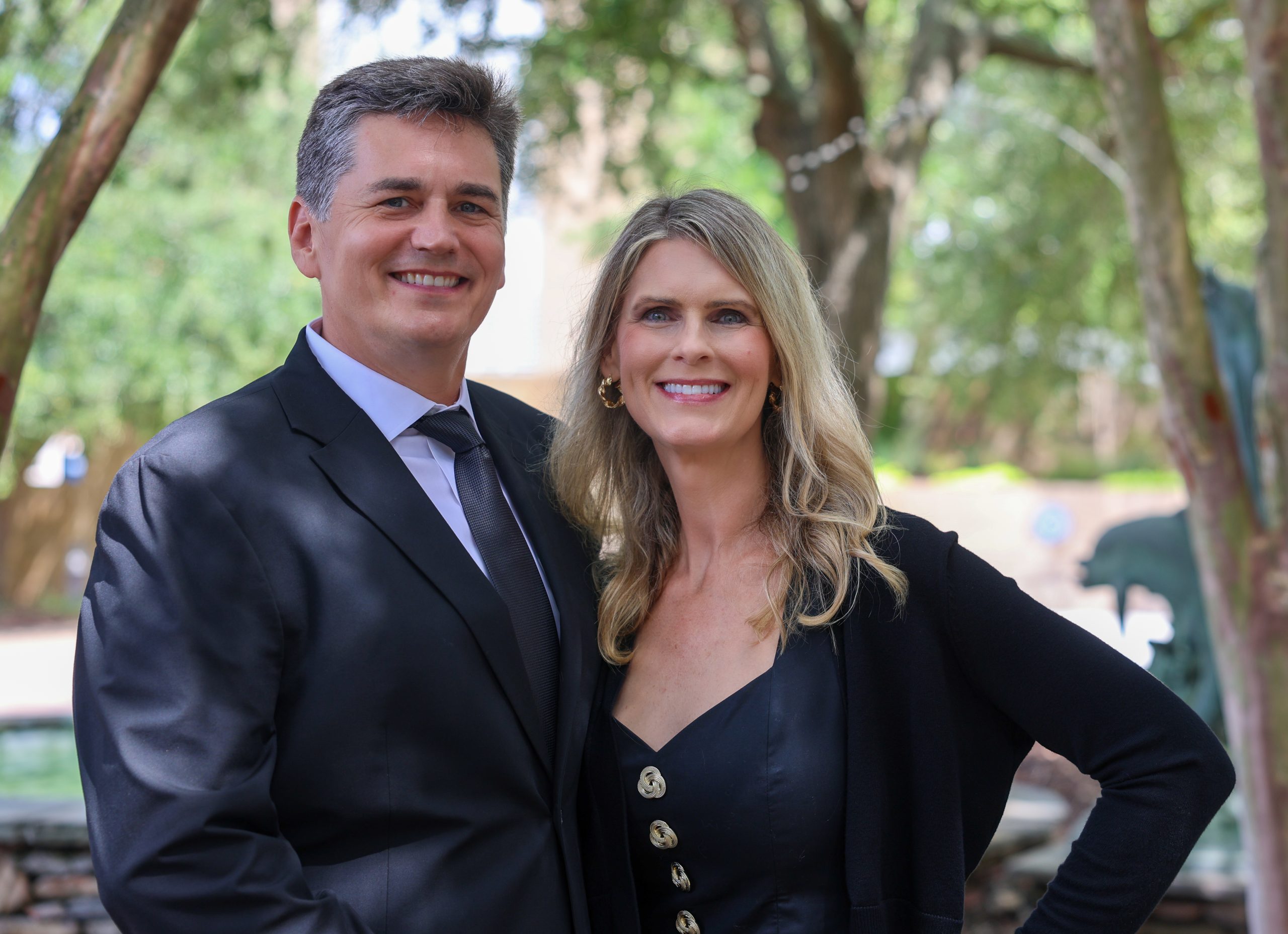 man and woman posing outside next to each other smiling