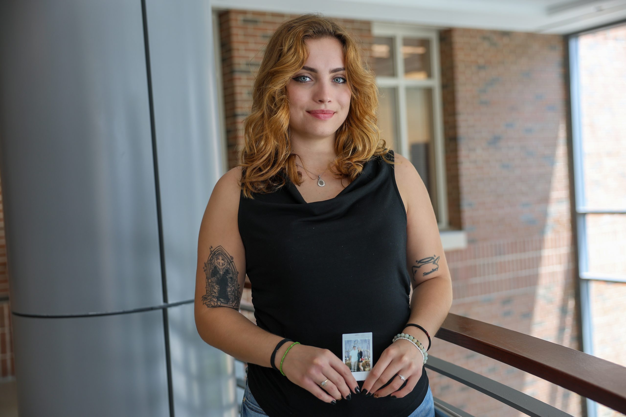 student holding polaroid of father on campus