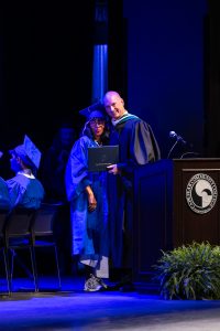 female graduate standing next to college president