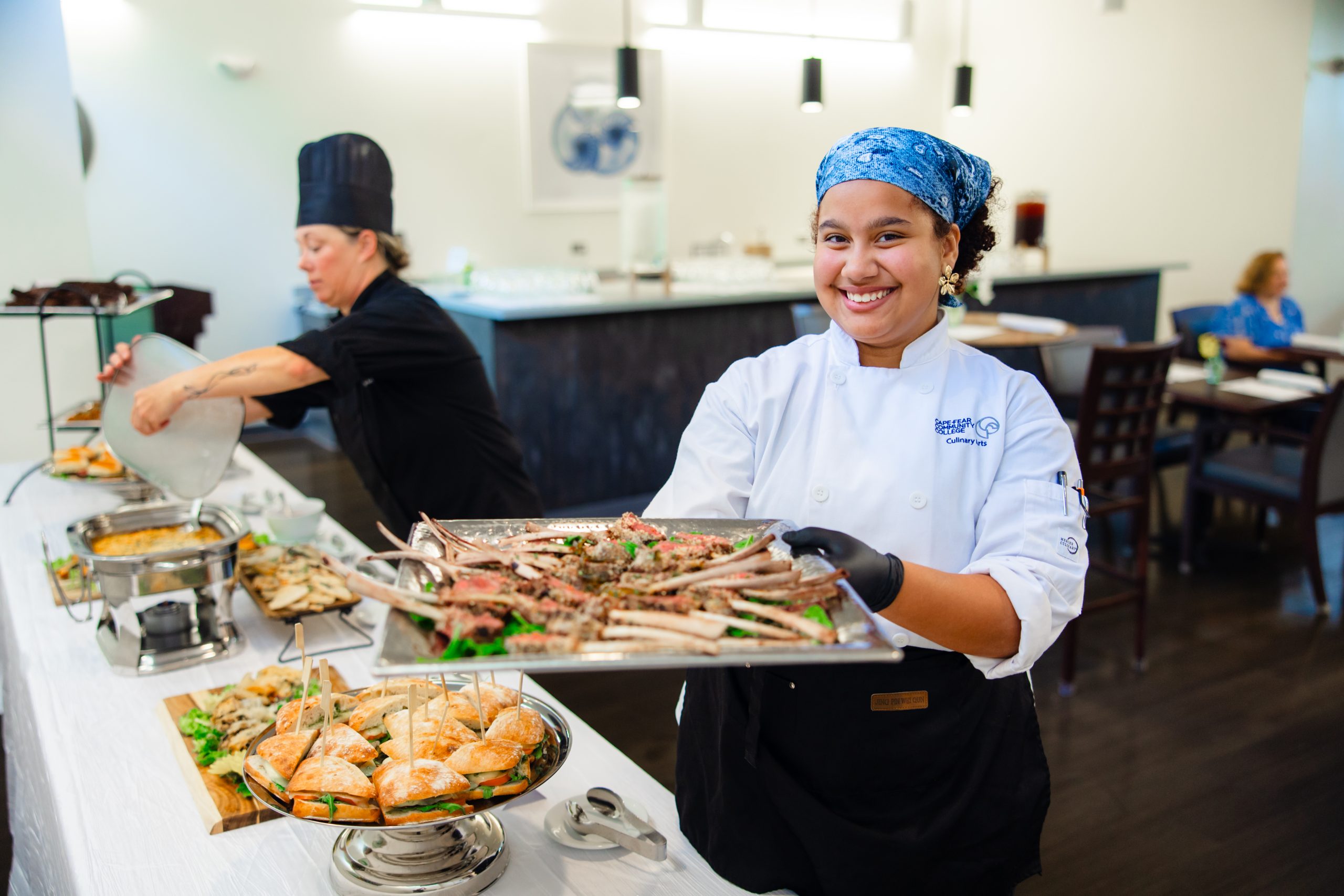 student holding dish of food in kitchen