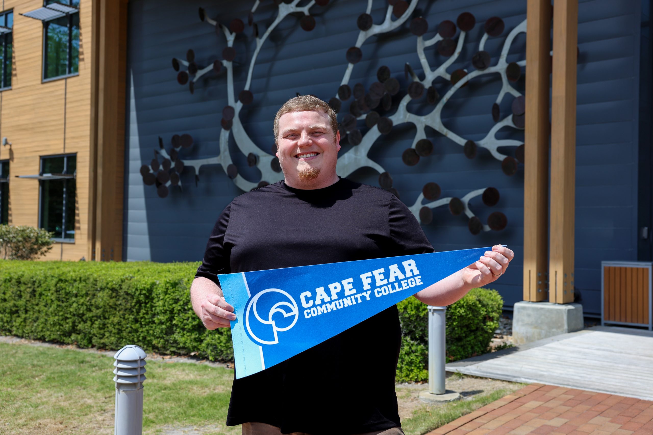 Nathan Divers holding CFCC sign at live oak bank campus